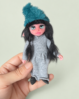 Iselune — sostenido en la mano como referencia de tamaño, fondo salvia suave y claro