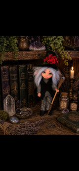 Thalvera Pixie artesanal con sombrero de rosa roja y báculo de amatista entre libros de magia y cristales
